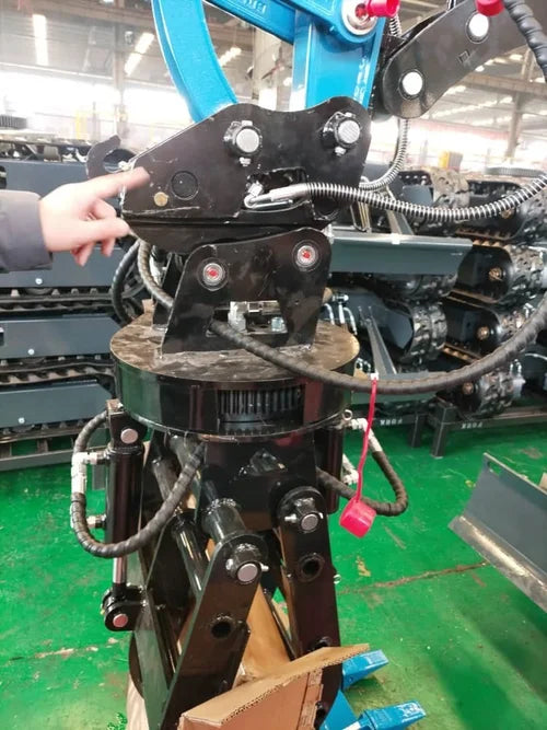 Rotary grapple in a manufacturing setting with a person's hand interacting with it.